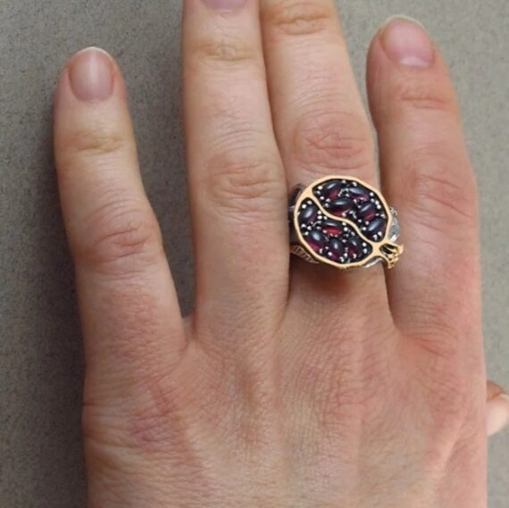 Hand wearing Aphrodite Pomegranate Ring, showcasing elegance