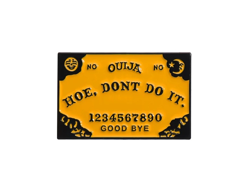 Enamel pin featuring the phrase 'Ouija Hoe, Don't Do It' against a backdrop of a stylized Ouija board design, perfect for adding a touch of occult humor to your attire.